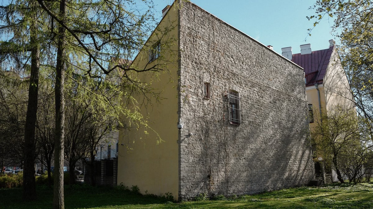 View of a sunlit historic stone wall in Tallinn's tranquil old town during spring.